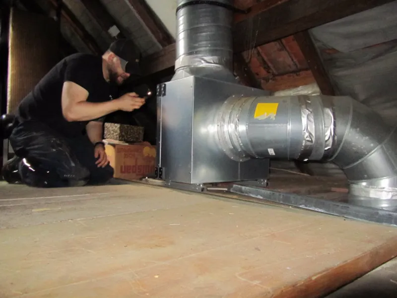 Kontrolle eines Abluftkanals mit Ventilatorbox im Dachboden